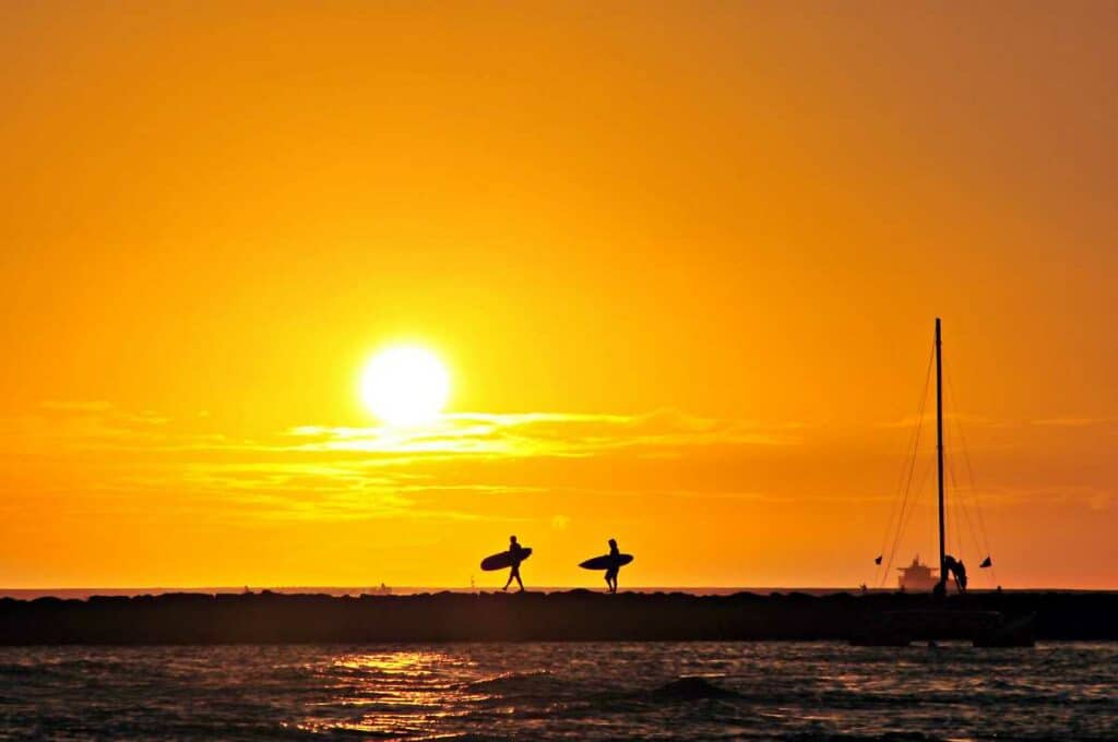 Surfers framed against a beautiful sunset at Waikiki Beach, Oahu