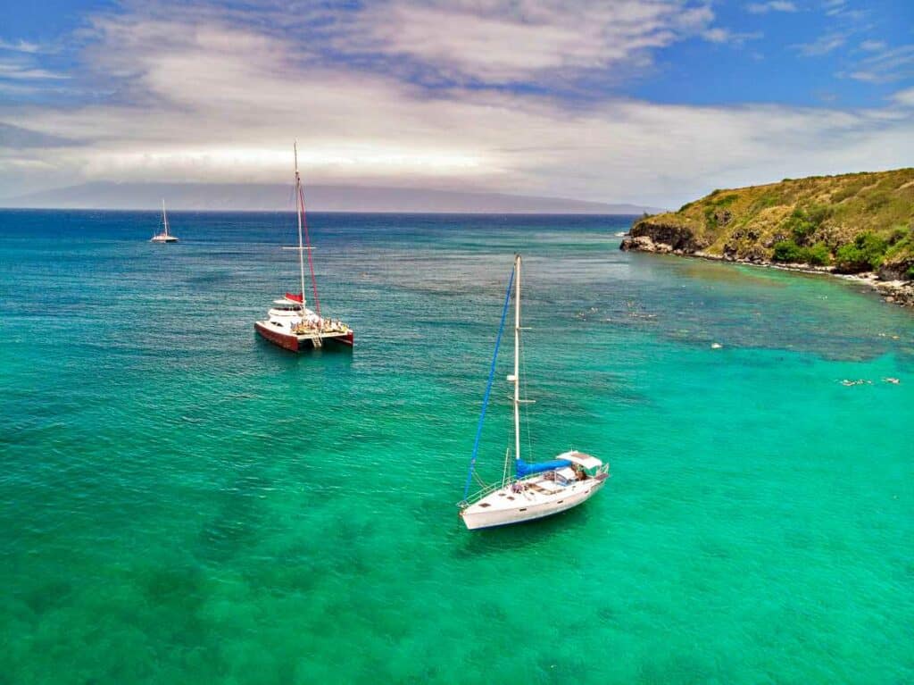 Sailboats and catamarans in the Honolua Bay heading out for whale watching in Maui Hawaii