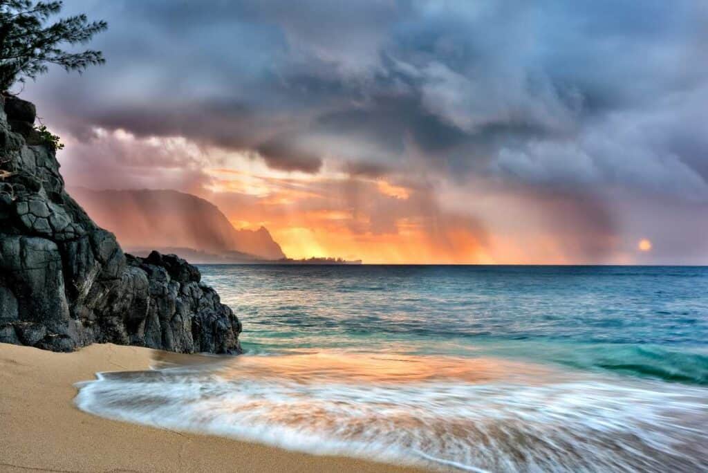 Dramatic colorful sunset at Hideaways Beach, Kauai, amidst gathering clouds