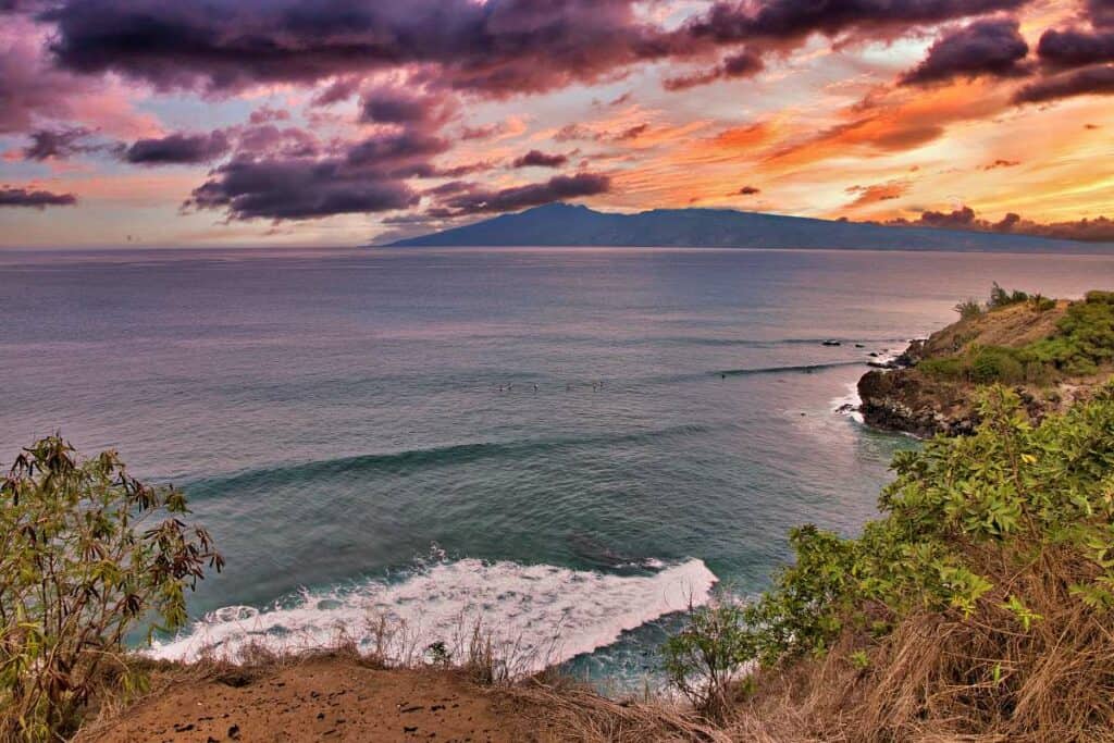 Surfers at sunset in Honolua Bay, Maui, HI