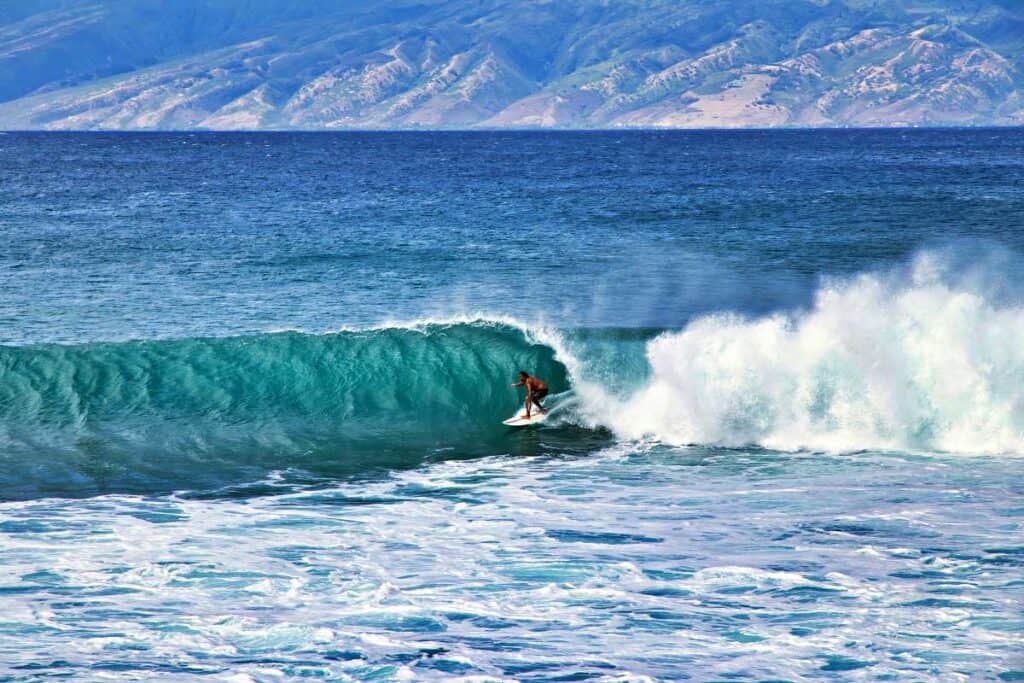 Zoom photo shot of a surfer riding towering waves at Honolua Bay, Maui, HI