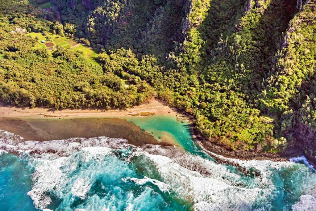 Beautiful Ke'e Beach surrounded by lush rainforest and crystal clear, blue ocean waters (helicopter view)