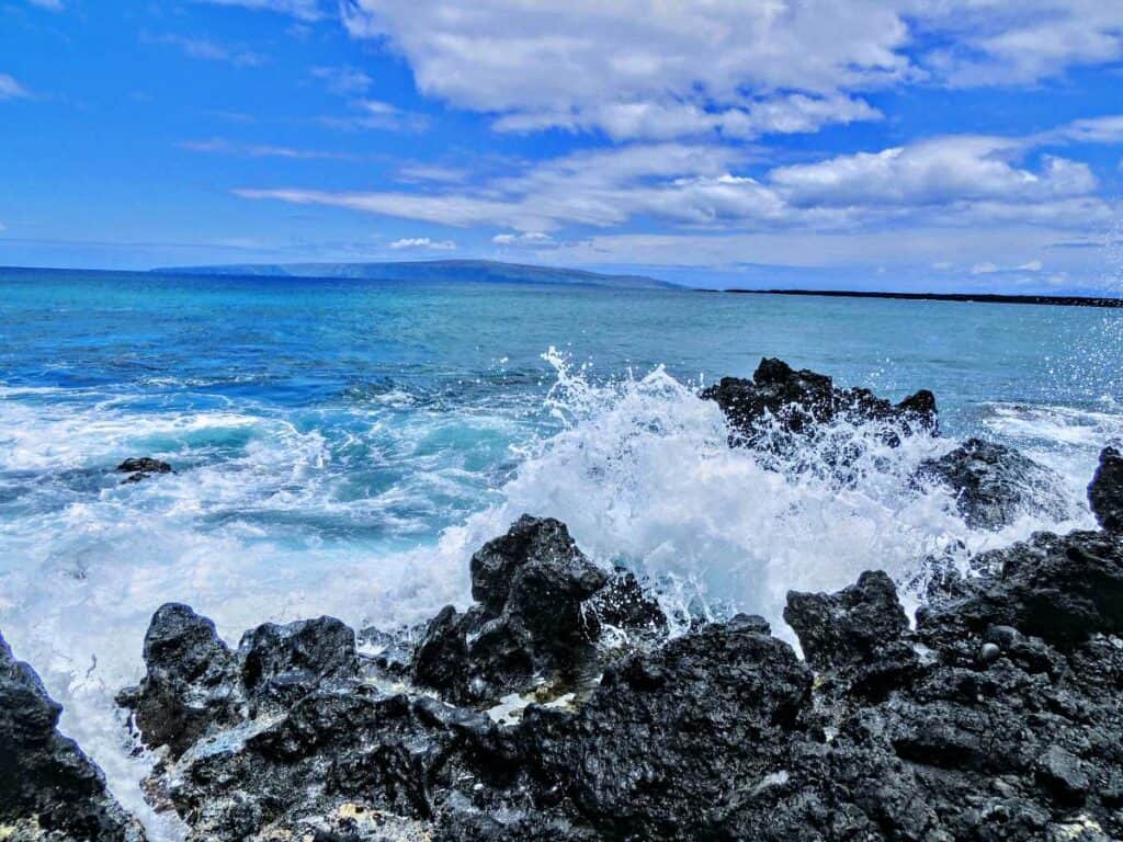 High surf conditions with waves crashing into the lava rocks at Maluaka Beach, Maui, HI