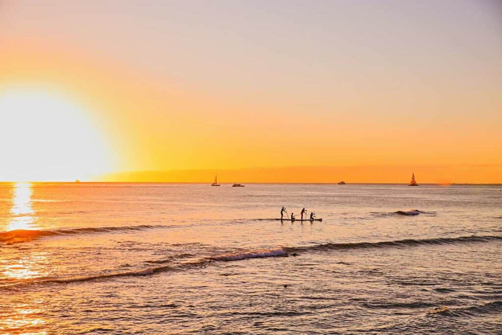 Family returning at sunset on paddle boards to Ala Moana Beach Park, Oahu, HI