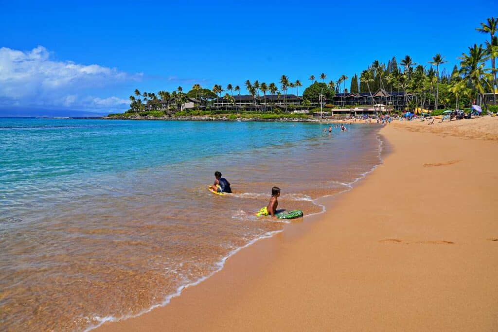 Children learning to boogie board and surf the gentle waves at Napili Beach, Maui, Hawaii