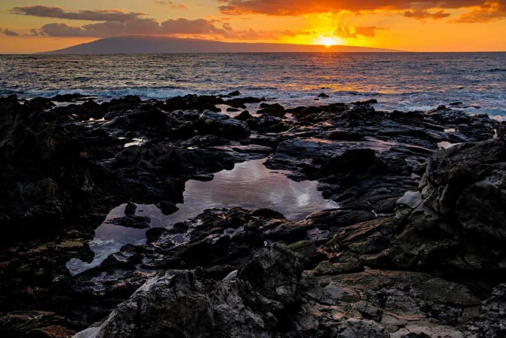 Watch a spectacular sunset from Napili Bay Beach, with the sun setting behind Lana'i island
