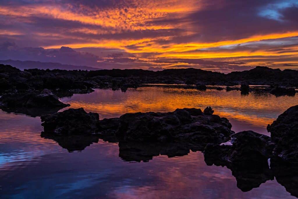 Stunning sunset colors fill the skies and are reflected in the calm waters of Shark's Cove tidepools