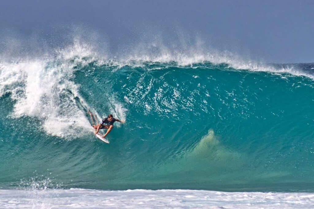 Professional surfer riding the towering waves on the Banzai Pipeline at Ehukai Beach, Oahu, Hawaii