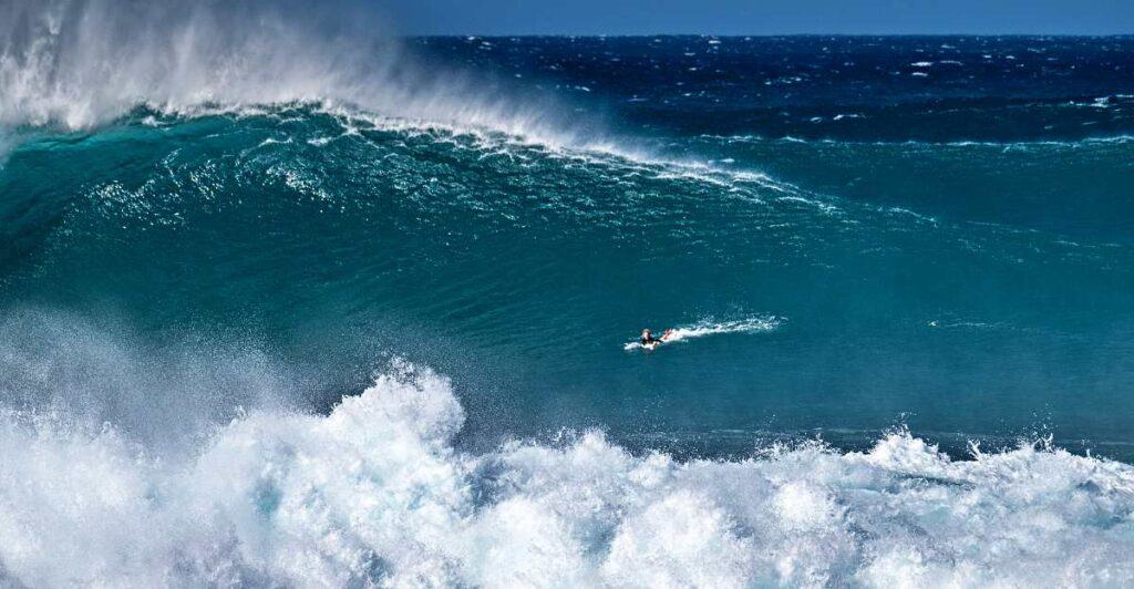 Surfer paddling to ride a giant wave on the Banzai Pipeline, Ehukai Beach, Oahu, Hawaii