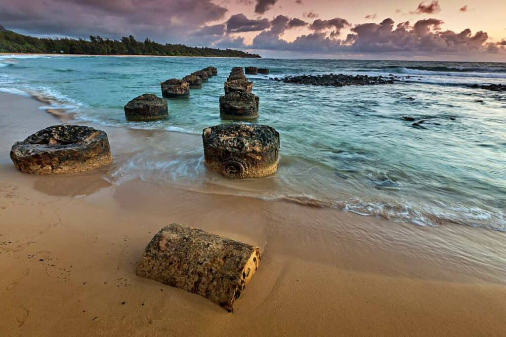 Remnants of an old pier extending into the ocean at Anahola Beach, Kauai