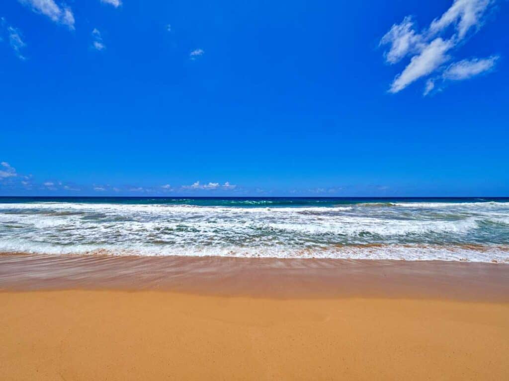 Golden sands and clear blue waters at Kealia Beach, Kauai