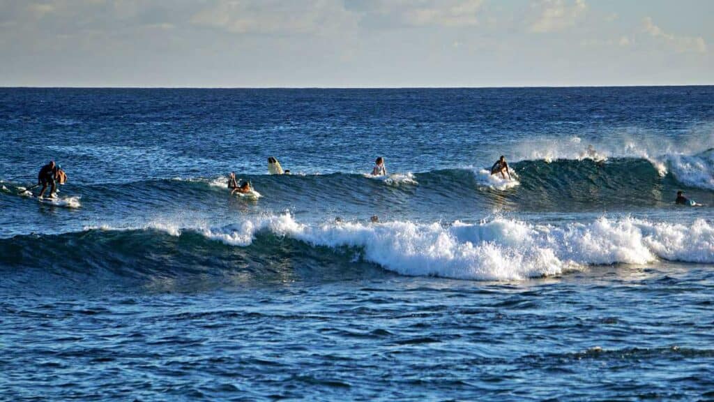 Surfers ride waves off Lawai Beach on the South Shore of Kauai